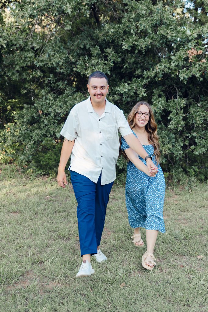Couple walking holding hands, smiling, and relaxed during golden hour at Lake Arcadia in Oklahoma