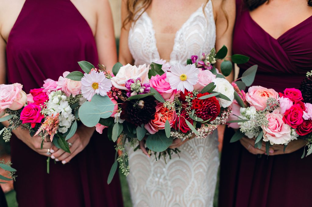 Bride and bridesmaids holding their bouquets close together in a cropped detail shot.