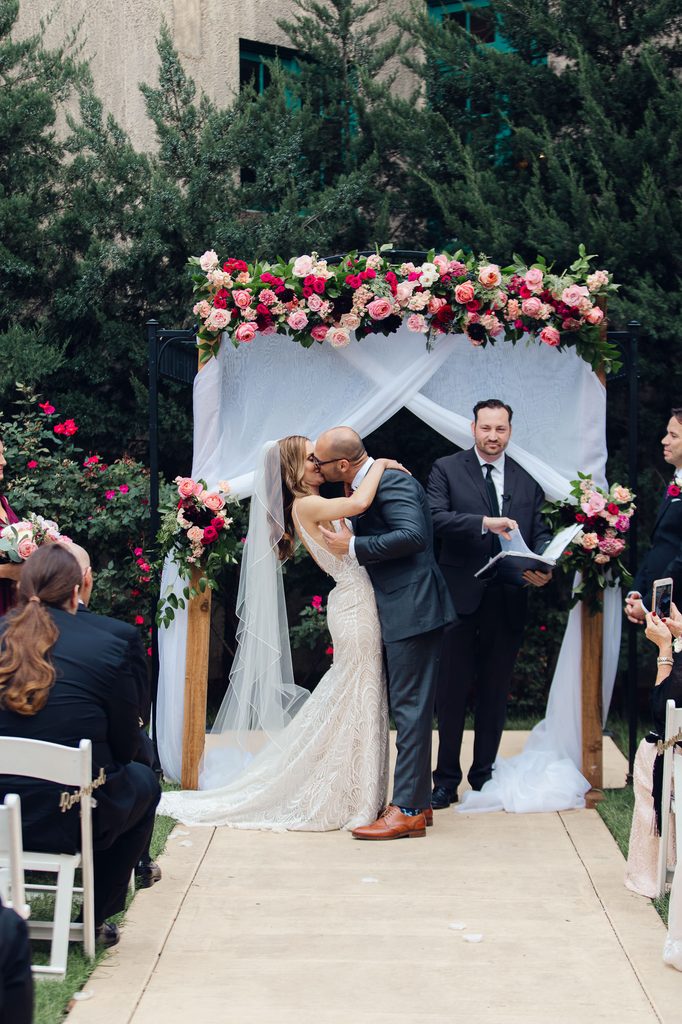 Megan & Keivan's first kiss as husband and wife, under the floral arch at their dresser mansion wedding.