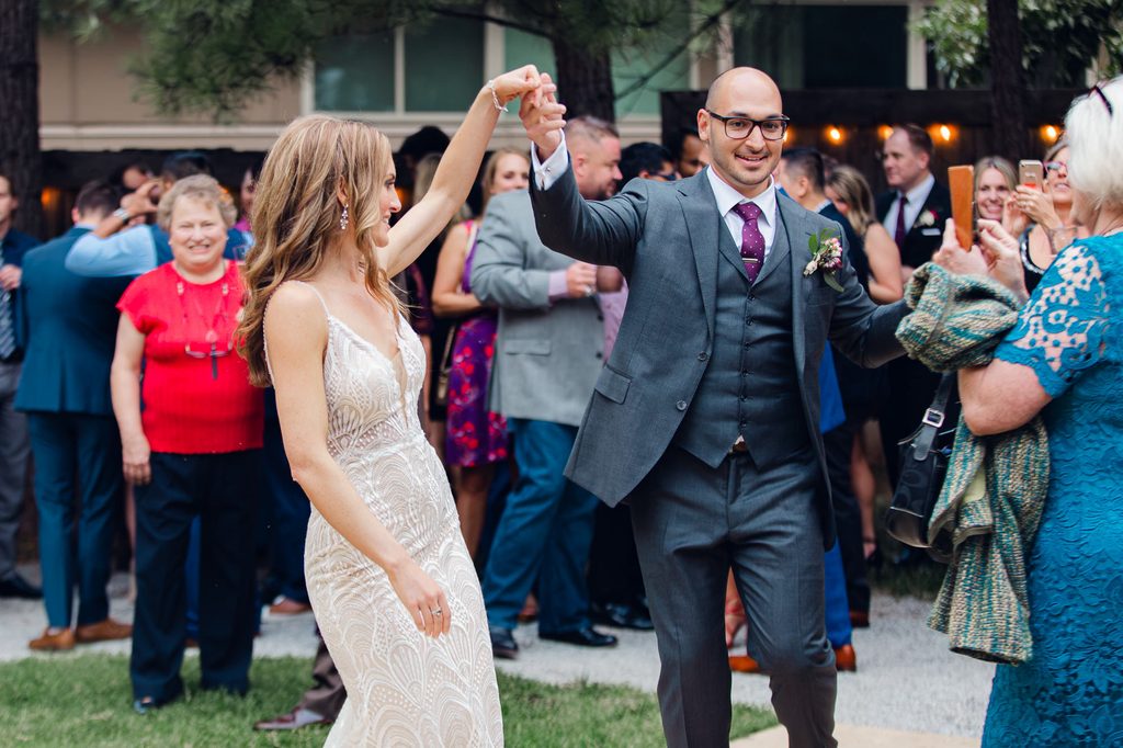 Keivan holding Megan’s hand overhead as they celebrate among their wedding guests. 